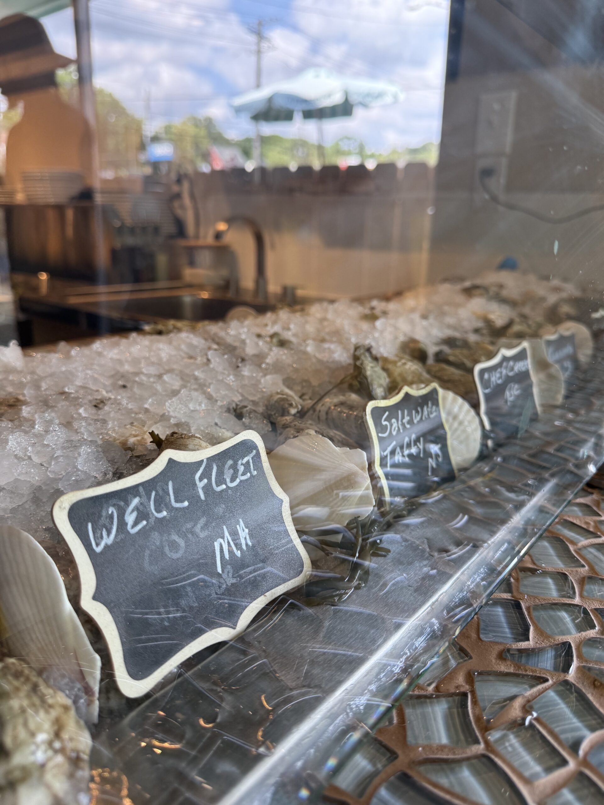 Fresh oysters displayed over ice with handwritten variety markers
